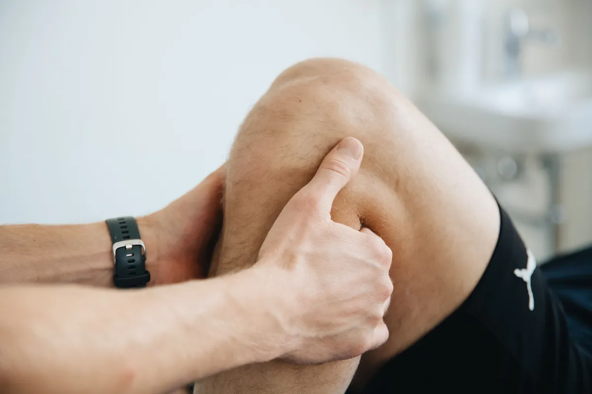 Traumatólogo explorando la rodilla de un paciente en consulta
