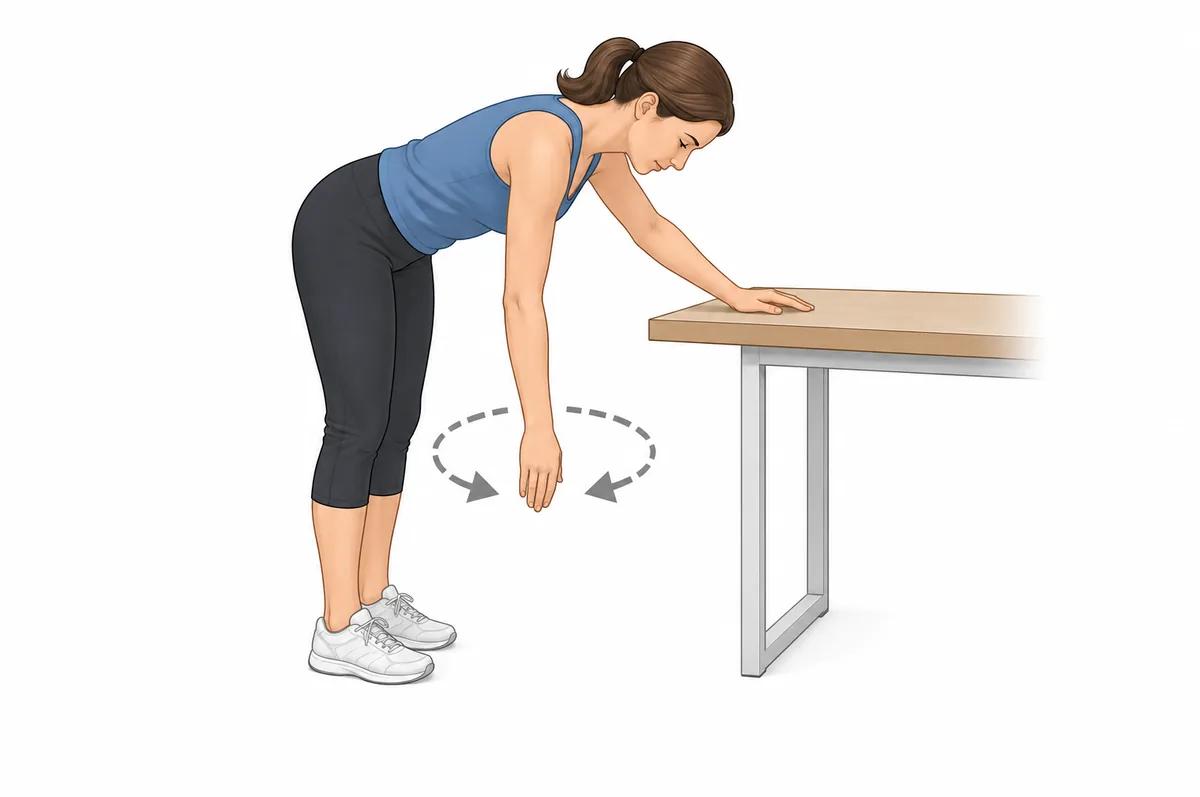 Mujer haciendo ejercicios pendulares para el hombro congelado, inclinada y apoyada en una mesa con el brazo colgando